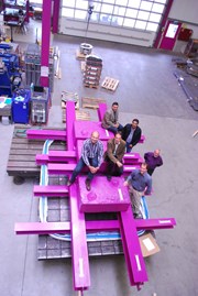 Pink steel and concrete weights reproduce the force of the relative movements that the 85 ITER bellows will have to withstand during operation of the Tokamak. Adding their weight to the ensemble: Igor Sekachev and Guillaume Vitupier (ITER Organization), Girish Kumar Gupta and Anil Bhardwaj (ITER India), and Werner Löhrer and Reto Löhrer (Kompaflex AG). (Click to view larger version...)