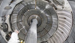 A researcher takes an upward view of the interior of NSTX, shown with the centre column. Copyright for all three photos: Princeton Plasma Physics Lab. (Click to view larger version...)