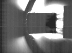 A 16 mm neon—deuterium pellet, indicated by an arrow, captured with a high speed camera as it travels from left to right at about 300 metres per second in a test stand at the Oak Ridge National Laboratory Pellet Lab. Photo: ORNL (Click to view larger version...)