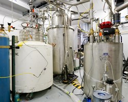A view of the test environment at the Spallation Neutron Source shows a white tank containing helium on the left, the prototype cryoviscous compressor pump in the middle, and the valve box, which monitors the flow rate to the pump, on the right. Photo: US ITER/ORNL (Click to view larger version...)