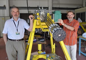 Sergei Putvinski (left) and fusion physicist François Saint-Laurent (IRFM) are not manning a Gatling machine gun. They stand next to the prototype DMS gun cartridge that will run its first tests at the end of the month. (Click to view larger version...)
