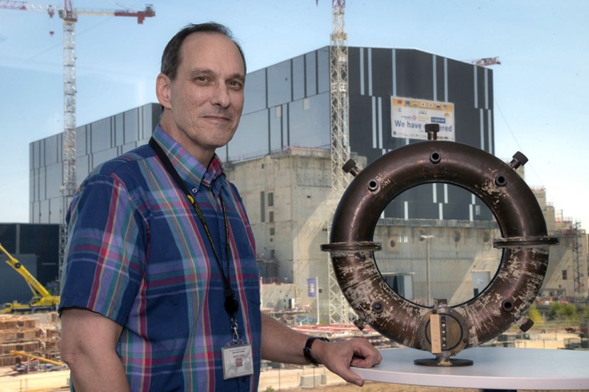 Chief Scientist Tim Luce against the backdrop of the ITER Tokamak Building, with the vacuum vessel of what could be the first attempt at building a tokamak outside the USSR in the late 1960s. ''Using a pipe bender, two postdocs at MIT made this perfect torus. Upon retirement, they bequeathed it to me ...'' (Click to view larger version...)