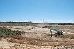 The Tokamak Pit seen from the east, with the concrete columns of the Poloidal Field Coils Winding Facility looming in the clear blue Provencal sky at the far end. (Click to view larger version...)