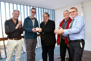 Liam Worth, Chair Mike Wykes, Wolfgang Obert and Robert Pearce award Stamos Papastergiou (centre) with a block of the ITER vacuum vessel and an ITER-coloured plastic duck in appreciation for his long-term support in the efforts to minimize the effects of water leaks on tokamaks. (Click to view larger version...)