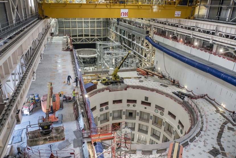 The ''assembly theatre'' is a vast space that encompasses the assembly and crane halls. In the foreground, the opening of the assembly pit; in the background, past the twin sector sub-assembly tools, the cryostat base is being groomed for the upcoming assembly operations. (Click to view larger version...)