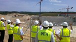 Under the sun of Provence, the delegation looks toward the Tokamak's anti-seismic "pillows" and listens to Tim Watson (pointing), director for Buildings & Site Infrastructure, as he relates the latest on ITER construction.