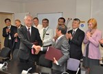 ITER DG Osamu Motojima and his Chinese counterpart, Luo Delong, shaking hands after signing PAs # 54 and 55. The team that accomplished the framework for these two contracts is watching the event.